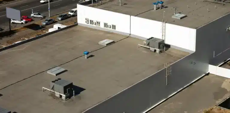 Aerial view of a large flat commercial roof with HVAC units, skylights, and roof access equipment.