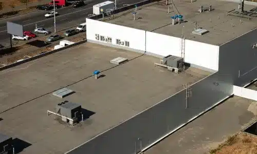 Aerial view of a flat commercial roof with HVAC units and roof penetrations on a large industrial building.
