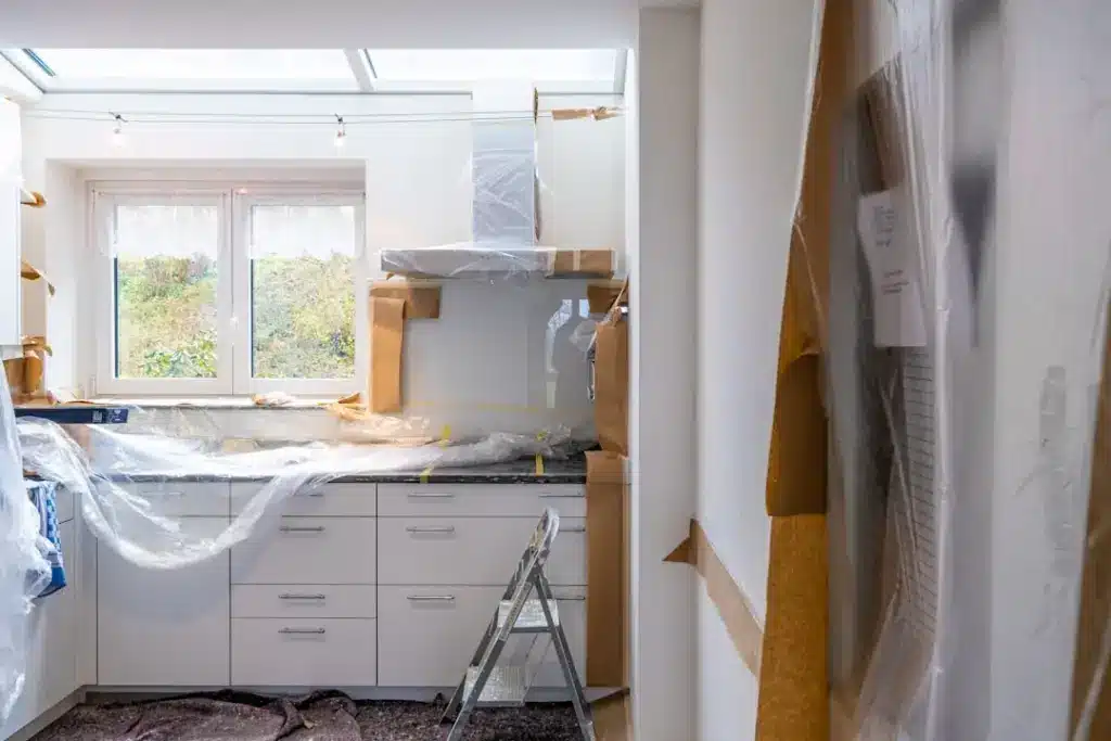Kitchen renovation in progress with cabinetry, protective coverings, and skylight installation visible.
