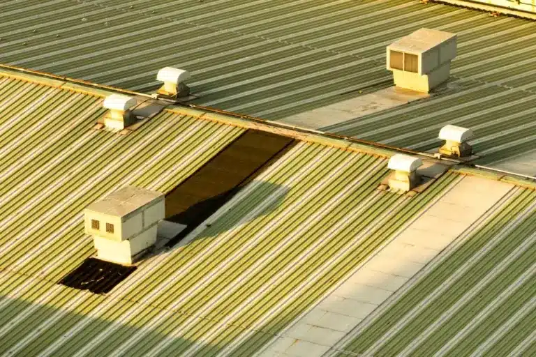 Aerial view of corrugated metal roof with multiple skylights and ventilation units installed.