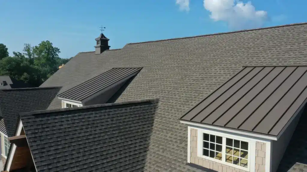 Residential home with multiple roof types including asphalt shingles and standing seam metal roofing.