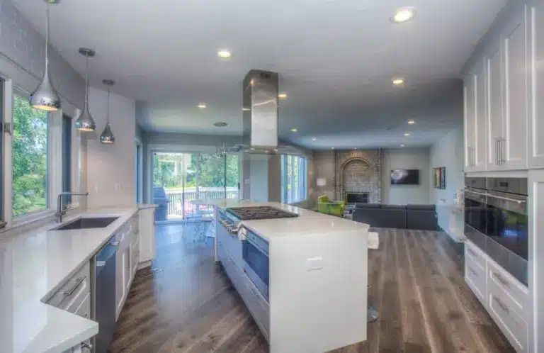 Open concept kitchen with white cabinetry, stainless steel appliances, and island overlooking living room.
